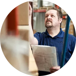 Man examining box on shelf with clipboard in his hand
