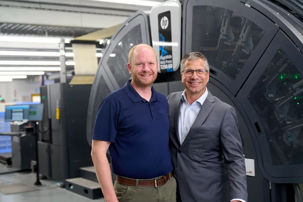 Chard Friesen and Jordan Toews in front of a HP web press