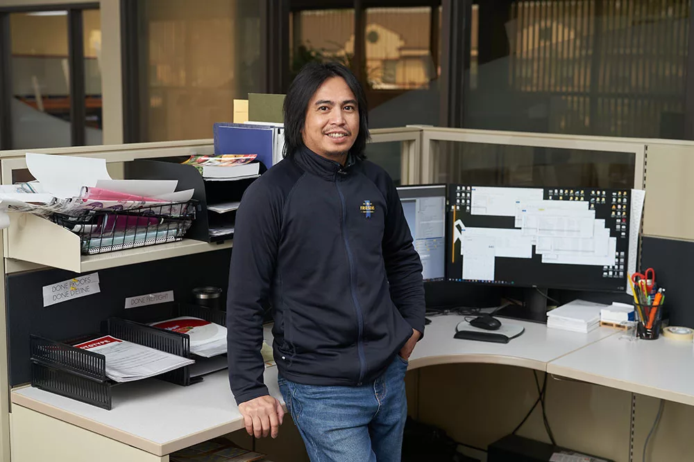 Smiling emplolee standing in office cubicle